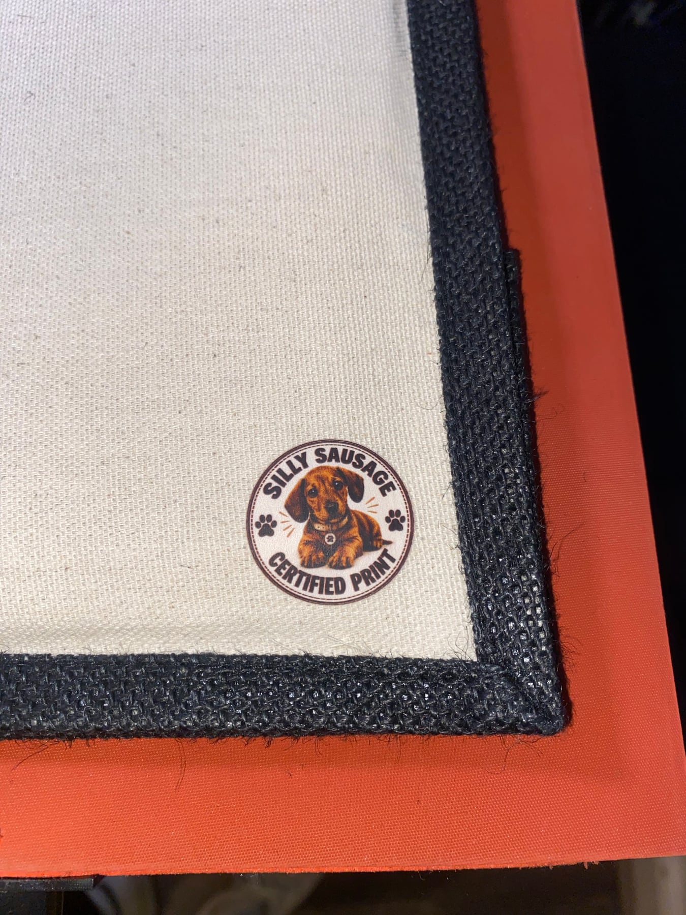 Close-up of the Silly Sausage Certified Print badge on a black-trim tote